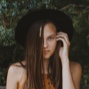 A portrait of a woman with dark brown hair wearing a black hat