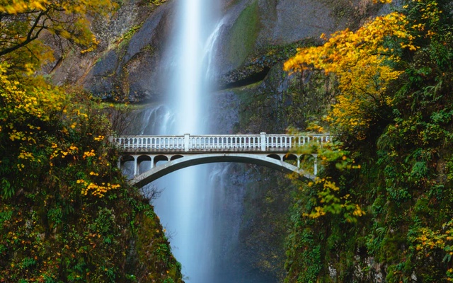 A bridge with a waterfall in the back