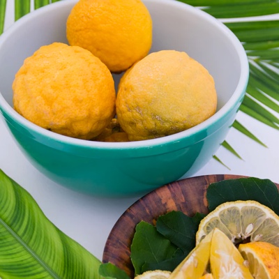 A bowl of uncut lemons with a plate of cut lemons