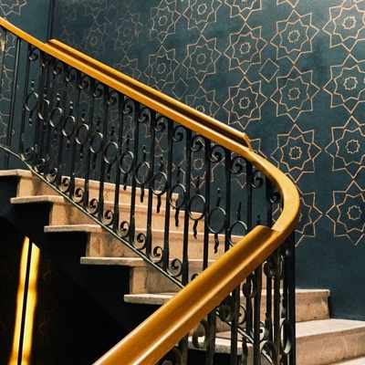 A wooden staircase with a trendy navy and gold wallpaper